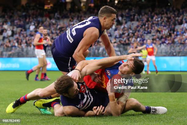 Eric Hipwood of the Lions gets tackled by Joel Hamling and Stephen Hill of the Dockers during the round 15 AFL match between the Fremantle Dockers...