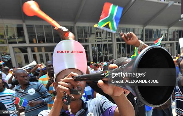 African football fans wave South African flags and vuvuzelas at a street party in Johannesburg on March 2, 2010 to celabrate 100days to the opening...