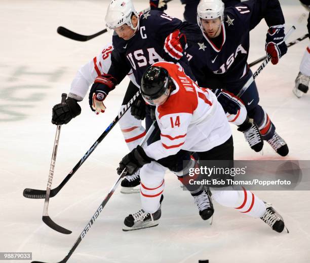 Roman Wick of Switzerland with Jamie Langenbrunner and Ryan Kesler of the USA during the ice hockey men's preliminary game between the USA and...