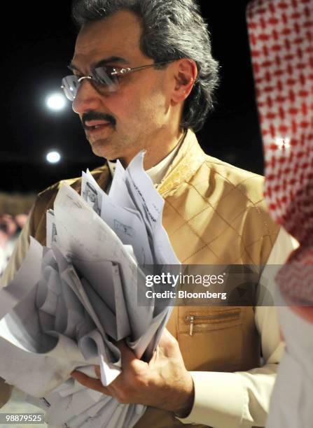 Saudi Prince Alwaleed bin Talal, holds requests from citizens who have asked for the Prince's assistance at the desert camp near Riyadh, Saudi...