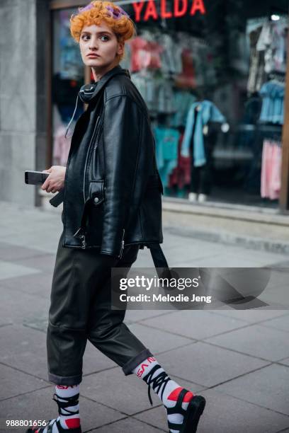 Model Tiko Jijelava exits a how with curlers in her hair and wears black headphones, a black leather jacket, black leather pants, Nasa socks, and...