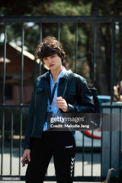 Model Tekla Chijavadze wears a black leather jacket, light blue button-up shirt, black leather backpack, and black Hummel sweatpants during...