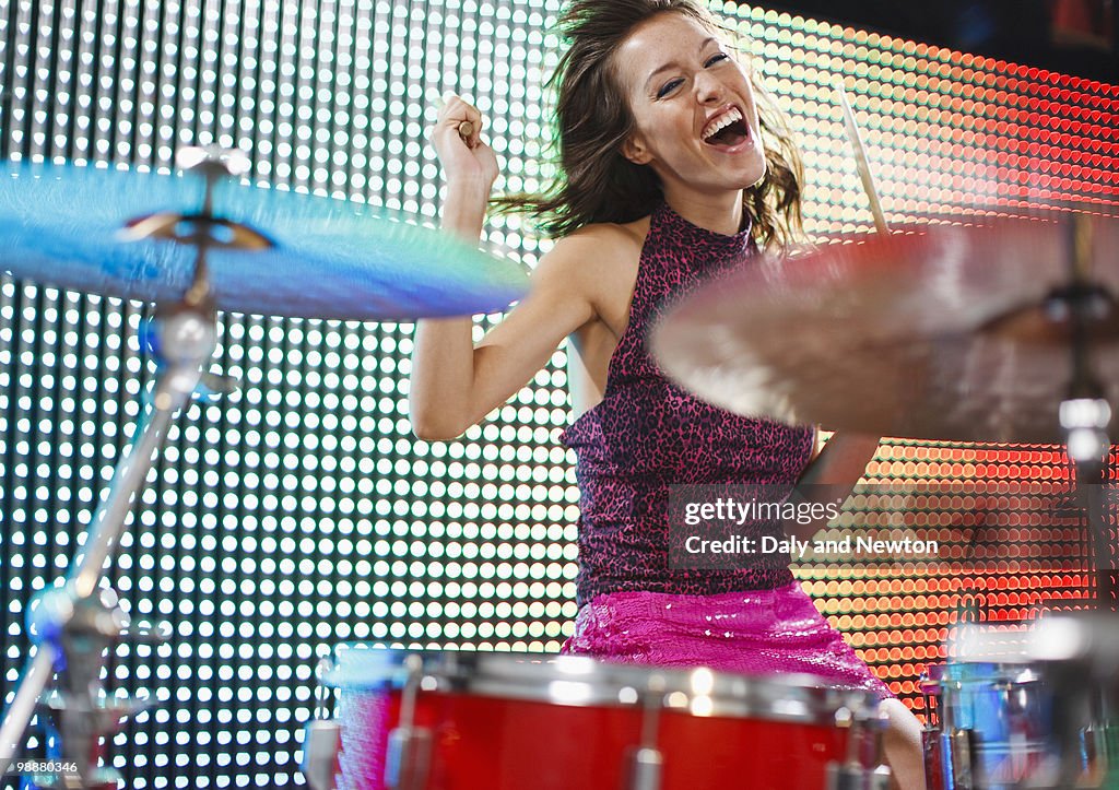 Young woman playing the drums, smiling