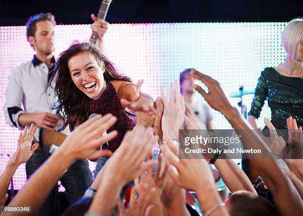 crowd reaching toward female singer on stage - boygroup stock-fotos und bilder