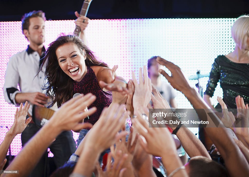 Crowd reaching toward female singer on stage