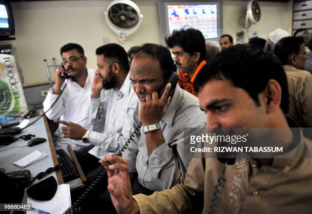 Pakistani stock dealers talk on phones in a brokerage house during a trading session in Karachi on May 6, 2010. The benchmark Karachi Stock Exchange...