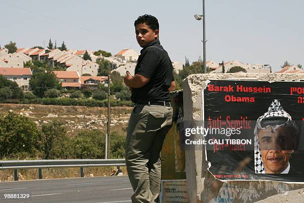 Backdropped by the West Bank settlement of Efrat near the biblical town of Bethlehem, a Palestinian youth stands next to posters hung up by...