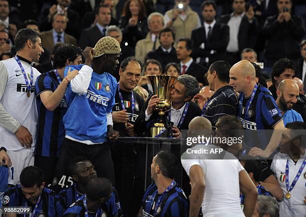 Inter Milan's Portuguese coach Jose Mourinho kisses the trophy as his players watch after they defeated AS Roma in the Coppa Italia final on May 5,...