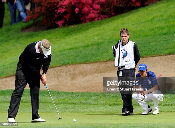 Matteo Manassero of Italy and caddie watch Ryder Cup captain Colin Montgomerie of Scotland on the eighth hole during the first round of the BMW...