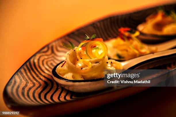 amuse bouche of fettuccini with trio of cheese sauce and crisped peppers - bouche stockfoto's en -beelden