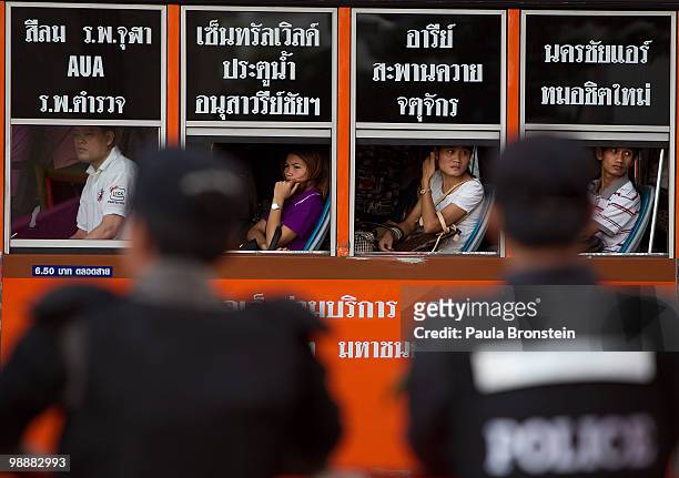 Thai workers stare out of the windows heading home from work on a city bus past the red shirt camp and the riot police on May 6, 2010 in Bangkok,...