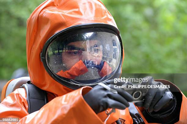 Member of the scientific police wearing gas and liquid-proof jumpsuits takes pictures during a simulation of a chemical bomb attack on May 6, 2010 at...