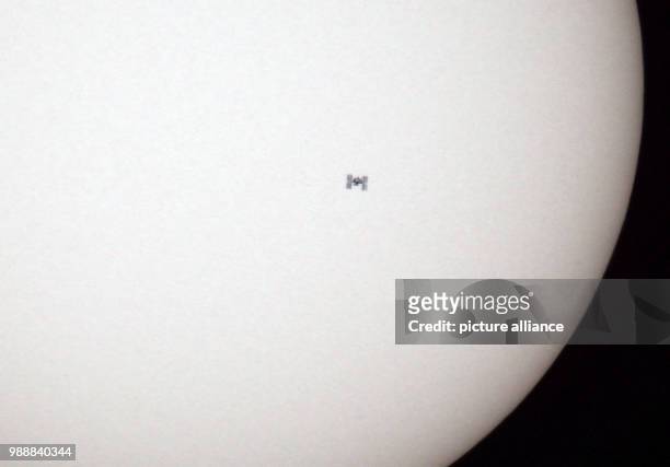 July 2018, Germany, Euskirchen: The International Space Station ISS passes the sun, resulting in its shadow briefly becoming visible on the sun disk....