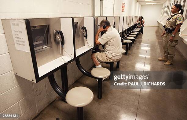 Detention Officer Rene Ansley looks on as visitors use a video phone to communicate during visiting hours with a friend or relative incarsarated...