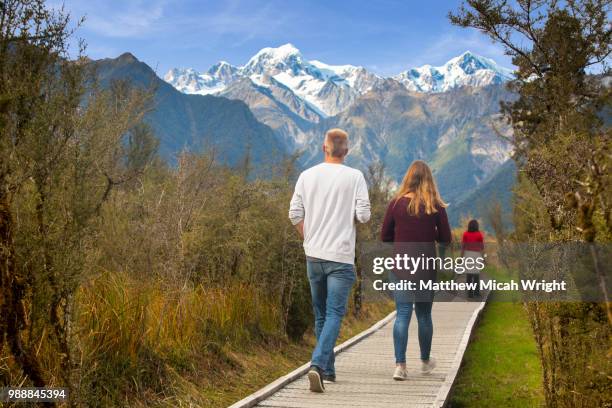 tourists take a scenic hike in lake matheson. the famous fox glacier is seen in the distance. - south westland bildbanksfoton och bilder