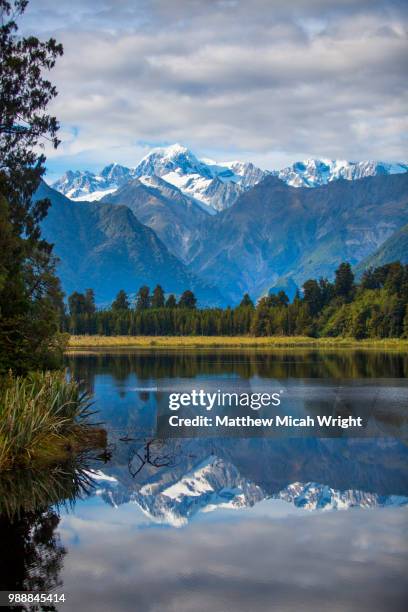 hikers explore the lake matheson trails. the lakes mirror reflections are a famous photo stop for visitors. - south westland bildbanksfoton och bilder
