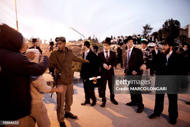 An Israeli border policeman stops a group of religious Israeli Jews from confronting Palestinians living in the mostly Arab Jerusalem neighborhood of...