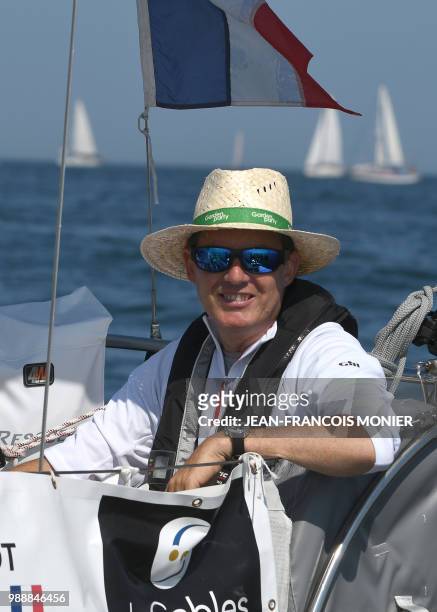 France's skipper Antoine Cousot sits at the helm on his boat "Metier Interim" as he sets off from Les Sables d'Olonne Harbour on July 1 at the start...