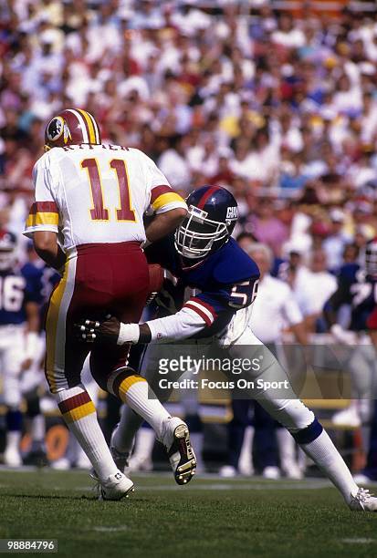 Linebacker Lawrence Taylor of the New York Giants has quarterback Mark Rypien of the Washington Redskins in his grasp circa 1990 during an NFL...