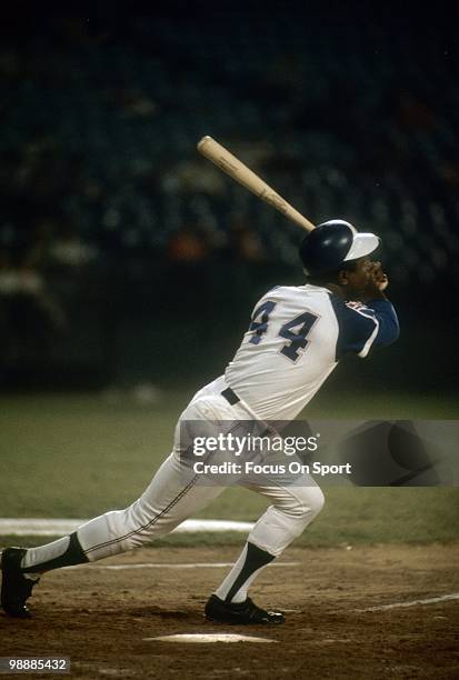 Outfielder Hank Aaron of the Atlanta Braves swings and watches the flight of his ball circa 1974 during a Major League Baseball game at...