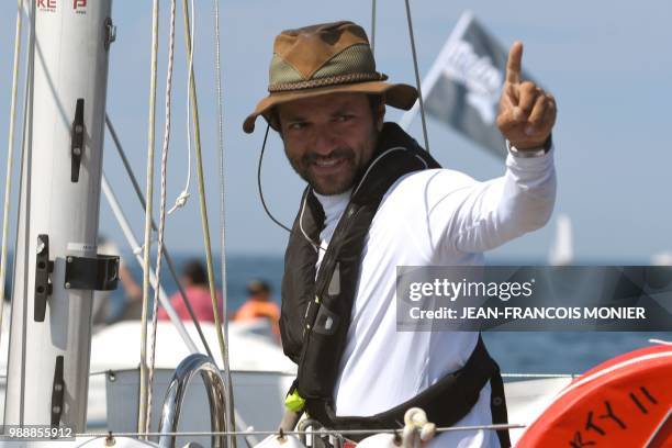 Palestine born, American Nabil Amra, gestures from his boat "Liberty II" as he sets sail from Les Sables d'Olonne Harbour on July 1 at the start of...