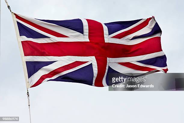 the british union jack flag flaps proudly in a stiff wind. - english flag stockfoto's en -beelden
