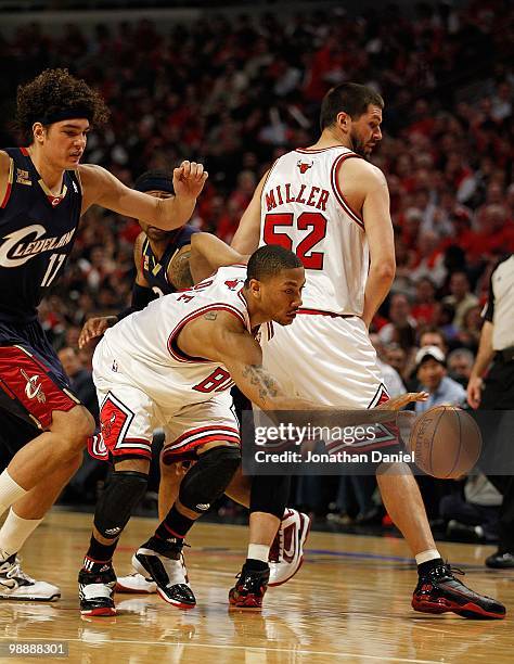 Derrick Rose of the Chicago Bulls moves around a screen set by Brad Miller and under pressure from Anderson Varejao of the Cleveland Cavaliers in...