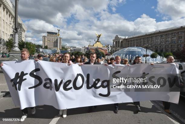 People carry a giant banner with an appeal to free Ukrainian film director Oleg Sentsov during a rally in Kiev on July 1 to demand the release Oleg...