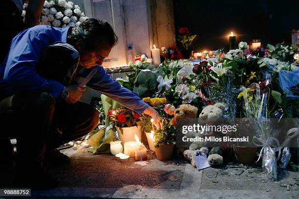 Man lights a candle in front of the Marfin Egnatia bank branch where three people were killed during demonstrations on May 6, 2010 in Athens, Greece....