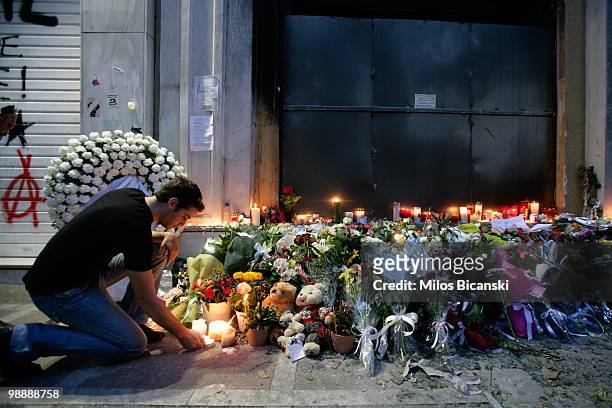 Man lights a candle in front of the Marfin Egnatia bank branch where three people were killed during demonstrations on May 6, 2010 in Athens, Greece....