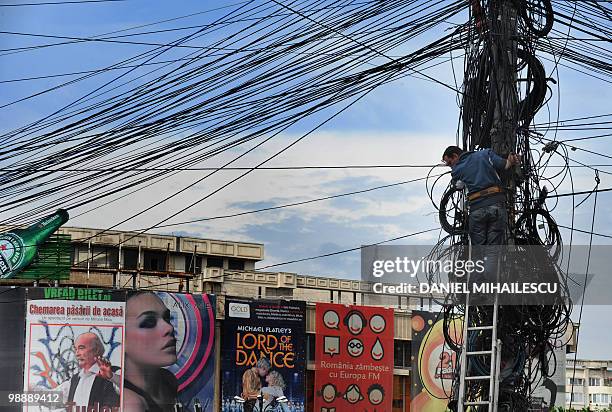 Romanian worker fixes communications cables on a pole downtown Bucharest, May 6, 2010. Romania will slash wages in the public sector by 25 percent...