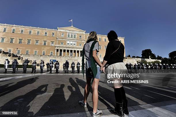 Two young women stand in front of riot police guarding the Greek parliament during a protest in Athens on May 6, 2010. More than 10,000 people...