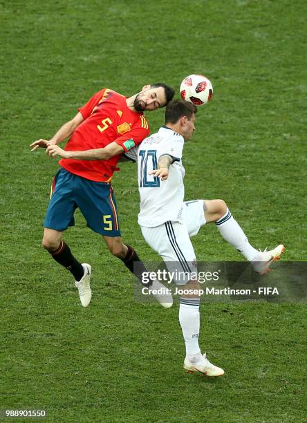 Sergio Busquets of Spain wins a header over Fedor Smolov of Russia during the 2018 FIFA World Cup Russia Round of 16 match between Spain and Russia...