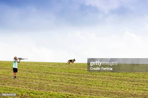 ein junge auf der jagd mit seinem hund auf einem bauernhof feld in am nachmittag licht. - air rifle stock-fotos und bilder