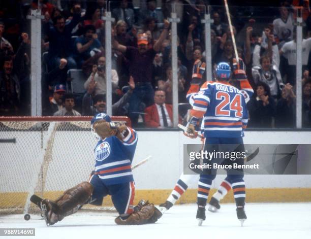John Tonelli of the New York Islanders scores past Tom Raulston and goalie Grant Fuhr of the Edmonton Oilers during the 1983 Stanley Cup Finals circa...