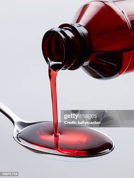 cough syrup pouring into spoon. - sciroppo foto e immagini stock