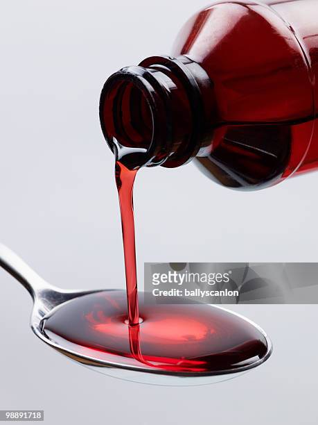 cough syrup pouring into spoon. - syrup stockfoto's en -beelden