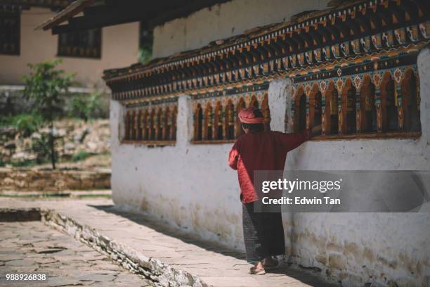 una vieja hembra de bhután en el templo orando en la rueda de oración - paro district fotografías e imágenes de stock