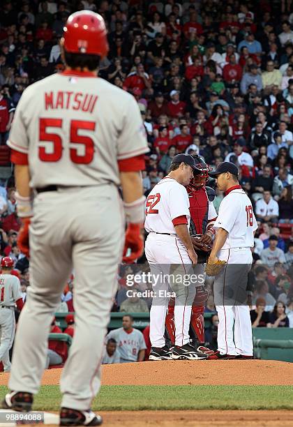 Daisuke Matsuzaka of the Boston Red Sox has a conference with catcher Victor Martinez and pitching coach John Farrell after Matsuzaka walked Hideki...