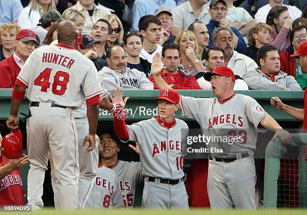 Torii Hunter and Juan Rivera of the Los Angeles Angels of Anaheim are congratulated by Ron Roenicke and Mike Butcher after they scored in the first...