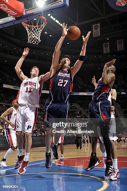 Zaza Pachulia of the Atlanta Hawks rebounds against Jonas Jerebko of the Detroit Pistons during the game at the Palace of Auburn Hills on April 7,...