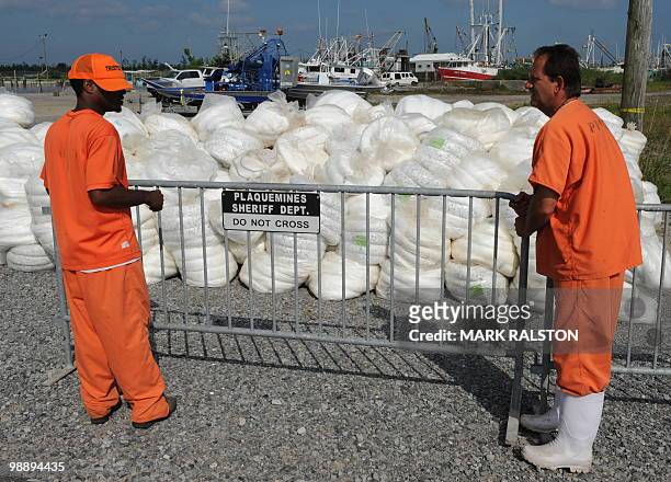 Inmate laborers erect a barrier fence around a stockpile of absorbent oil booms in the port of Venice, that will be used to soak up some of the oil...
