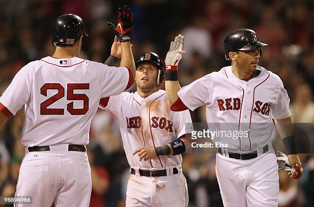 Marco Scutaro and Dustin Pedroia of the Boston Red Sox are congratulated by teammate Mike Lowell after they both scored in the fifth inning against...