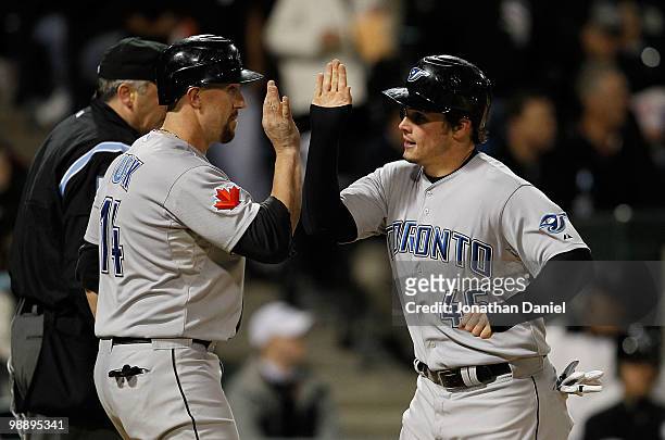 Travis Snider of the Toronto Blue Jays is congratulated by teammate John Buck after scoiring a run in the 5th inning against the Chicago White Sox at...
