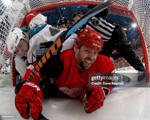 Kent Huskins of the San Jose Sharks gets tied up with Tomas Holmstrom of the Detroit Red Wings in the net during Game Four of the Western Conference...