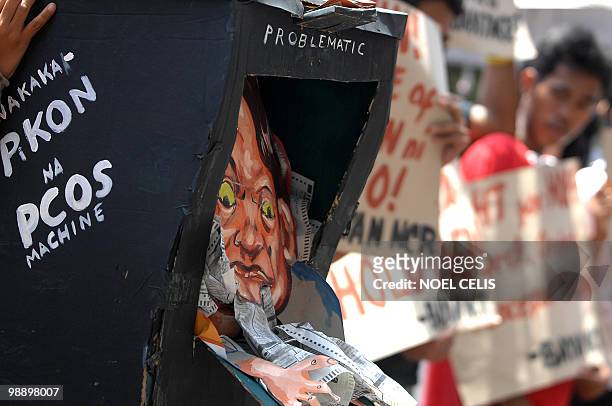 An activists holds a mock election counting machine during a protest in front of the Commission on Elections building in Manila on May 7, 2010. The...