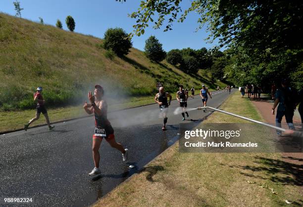 An Athlete cools off with spray of water in the run leg inside Holyrood Park during the IRONMAN 70.3 Edinburgh Triathlon on July 1, 2018 in...