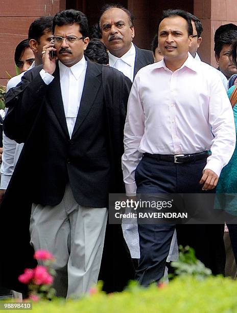Reliance Dhirubhai Group Chairman Anil Ambani walks with officials as he leaves the Supreme Court in New Delhi on May 7 after hearing judgements in a...