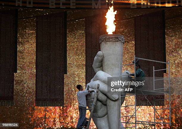 Picture taken on May 6, 2010 shows Russian men doing restoration work on the eternal flame at the Mamayev Kurgan memorial complex for Soviet Soldiers...