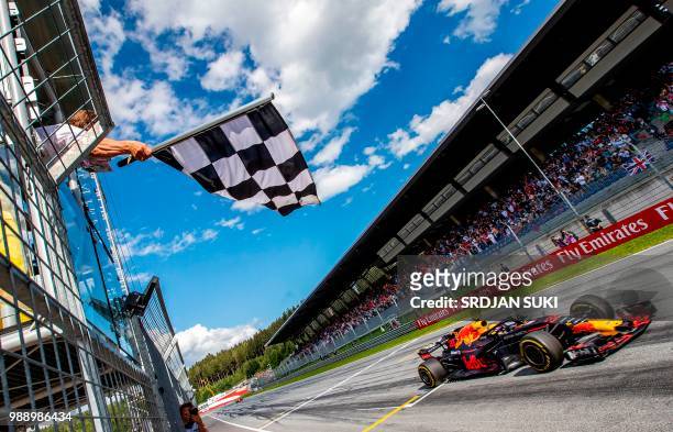 The flagman waves the chequered flag as Red Bull's Dutch driver Max Verstappen crosses the finish of the Austrian Formula One Grand Prix in...
